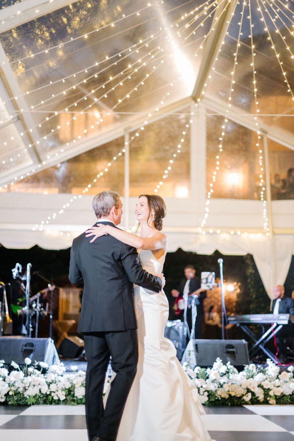 newlyweds have their first dance under clear top tent with black and white dance floor.