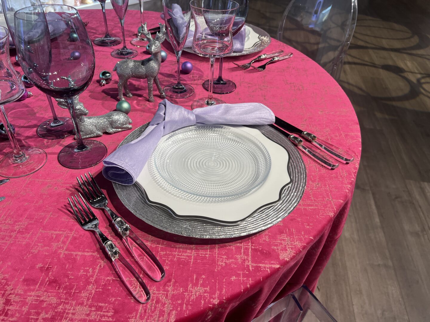 holiday table setting with magenta velvet linen and clear and silver china and flatware. 
