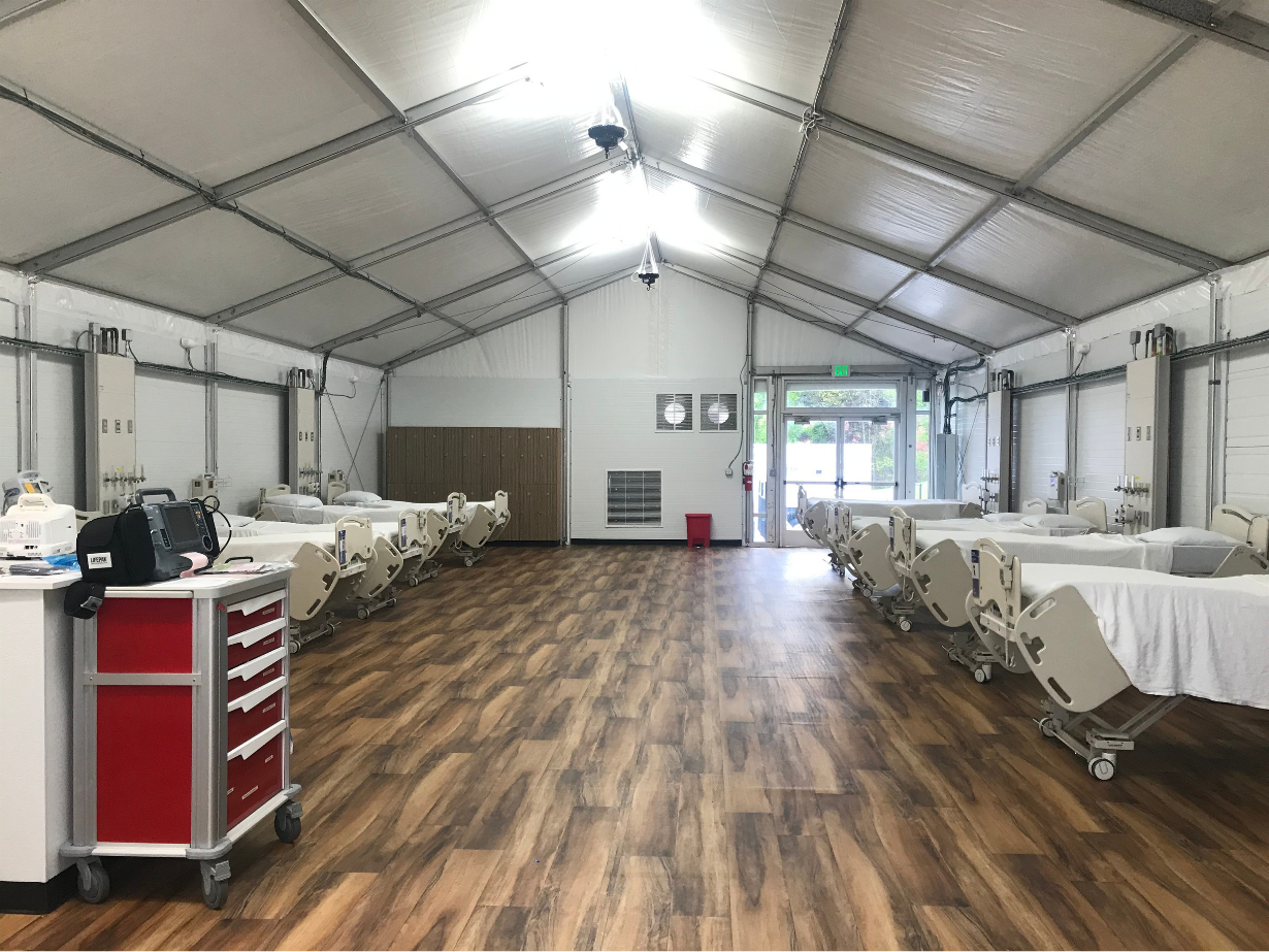 Interior of a weatherproof emergency response structure equipped with medical beds and specialized care infrastructure.